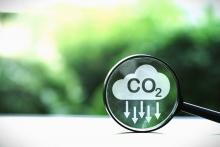 Introduction to Emission Reduction Credits , Photo co2 reducing icon inside magnifier glass on greenery background